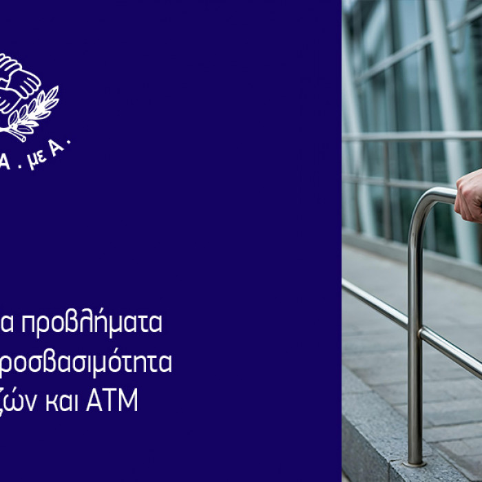 άτομο σε αμαξίδιο κρατά χειρολαβή (διακρίνεται μόνο το αριστερό χέρι και η αριστερή ρόδα), σε διάδρομο, τζαμαρίες στο βάθος